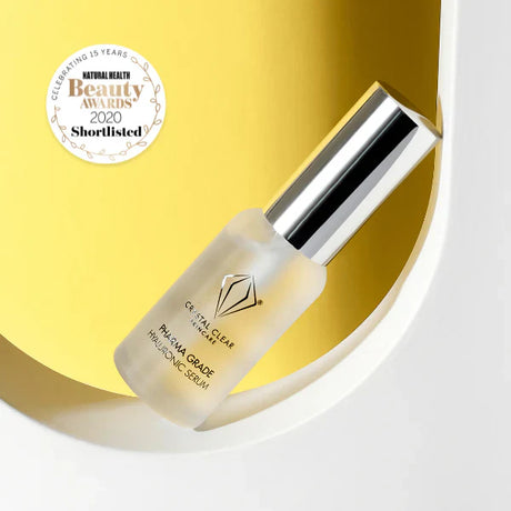 Vit flaska med svart text, stående på ljus och gul bakgrund – ett serum som binder fukt och stärker hudens naturliga barriär.