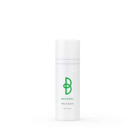 Vit tub med svart text, stående på ljus bakgrund – en dagkräm för torr hud som minskar rynkor och ger näring och lyster.