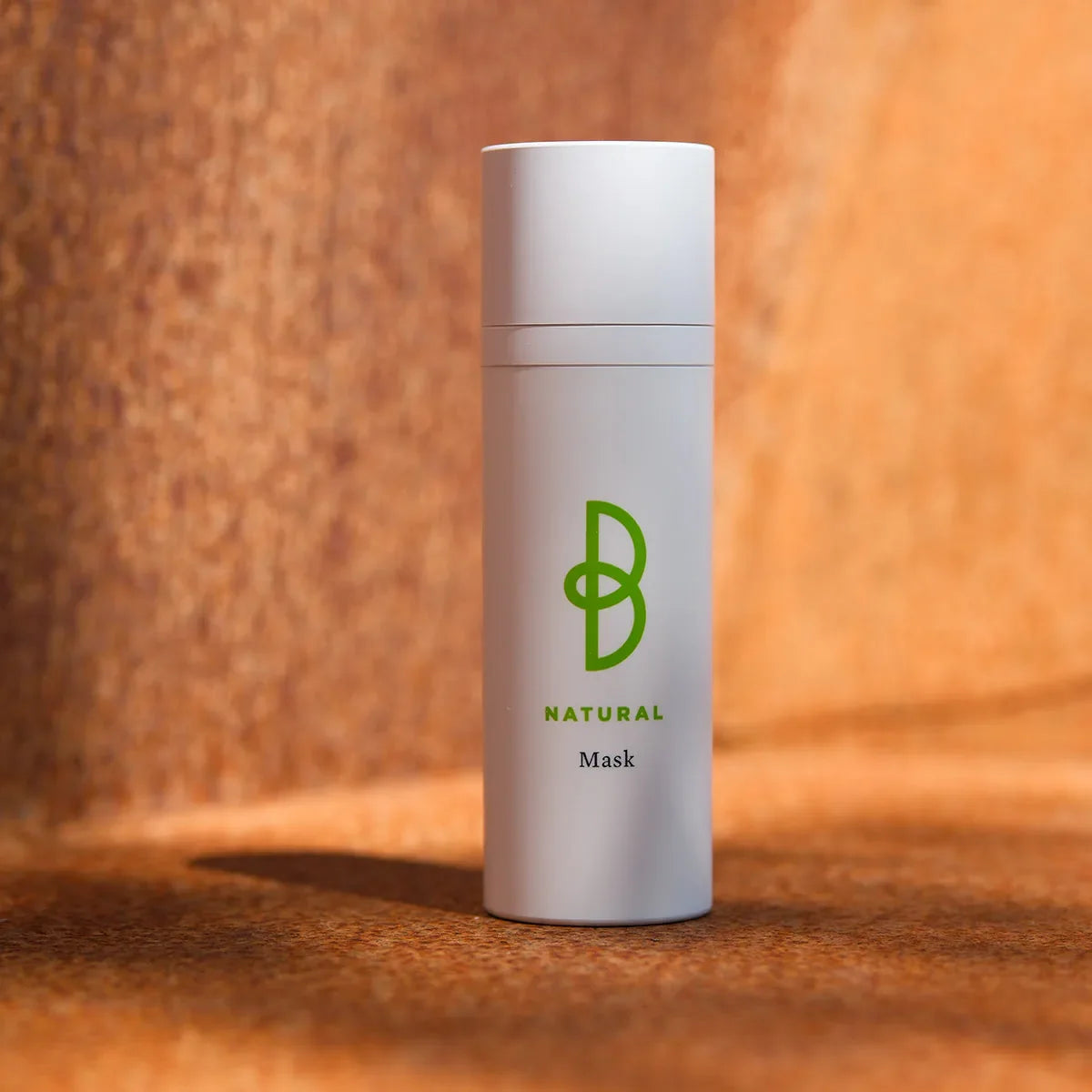 Vit flaska med svart text, stående på mörk bakgrund – en uppstramande ansiktsmask som jämnar ut hudtonen och förbättrar hudens elasticitet.