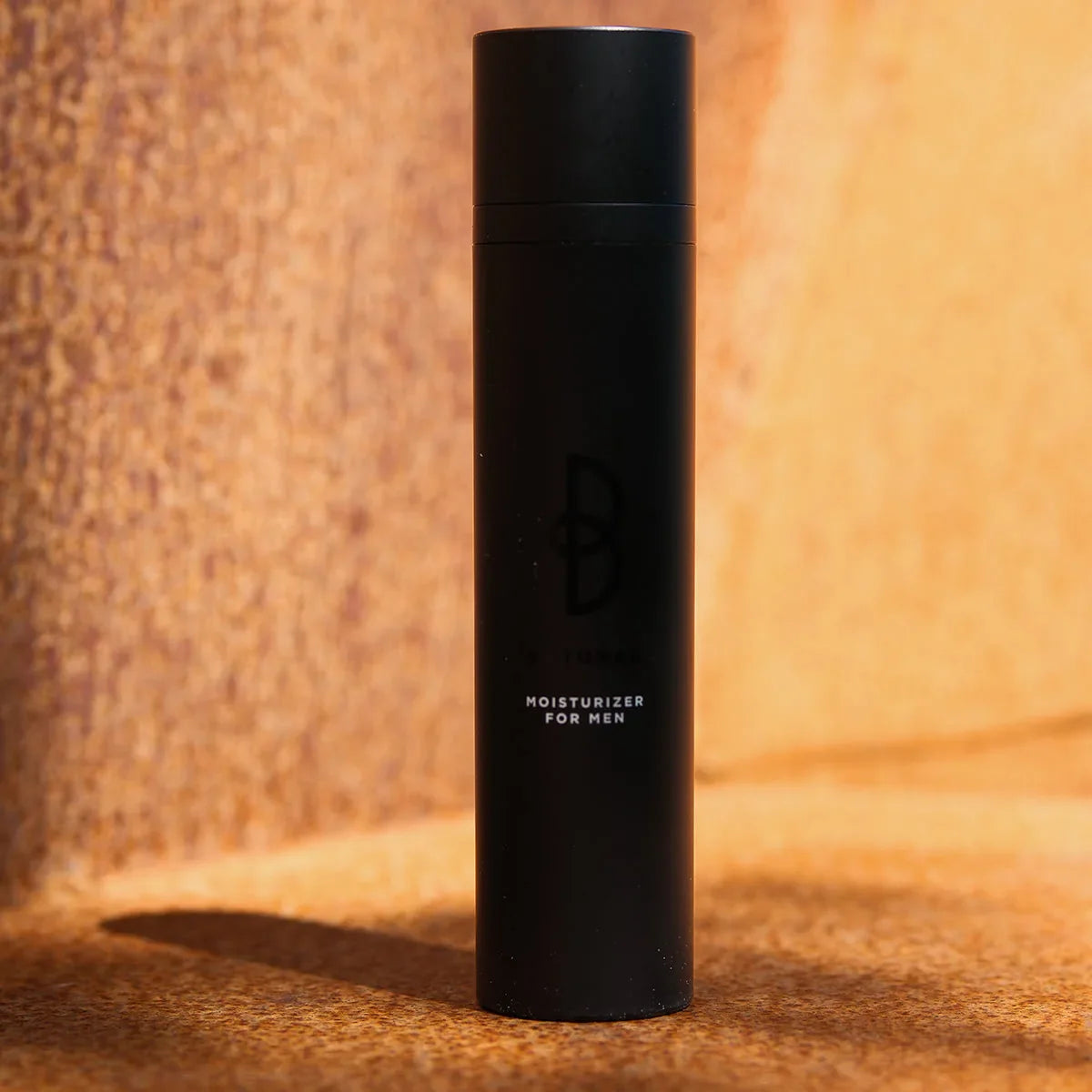 Svart flaska, stående på mörk bakgrund – en återfuktande kräm som minskar synliga rynkor och ger en fräsch hudton.