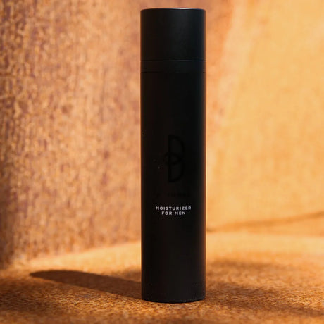 Svart flaska, stående på mörk bakgrund – en återfuktande kräm som minskar synliga rynkor och ger en fräsch hudton.