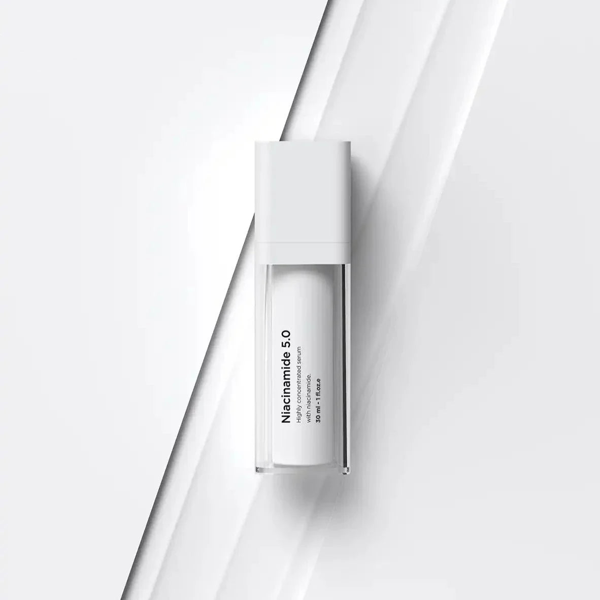 Vit flaska med svart text, stående på ljus bakgrund – ett serum som reducerar akne och förbättrar hudens balans.