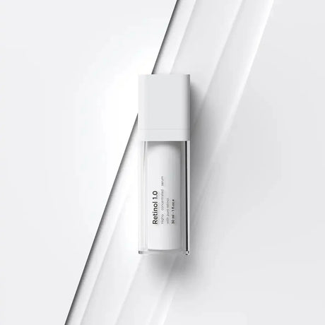 Vit flaska med svart text, stående på ljus bakgrund – ett serum som reducerar mörka fläckar och stärker huden.