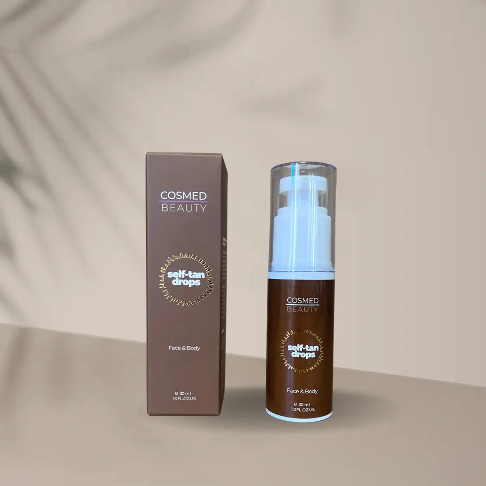 En närbild av en brun pappkartong med produktnamnet "Self Tan Drops Cosmed Beauty 30 ml" tryckt på framsidan. Bredvid kartongen står själva produkten – en pumpflaska – framme på en ljus bakgrund, vilket visar tydligt att produkten är redo att användas.