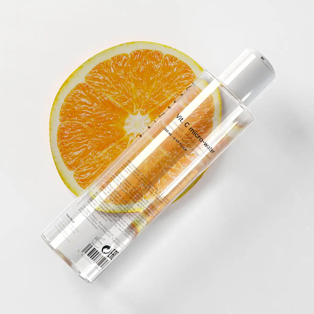 Vit flaska med svart text, stående på ljus bakgrund – en ansiktsprodukt som förebygger fotoåldrande och ger en jämn hudton.