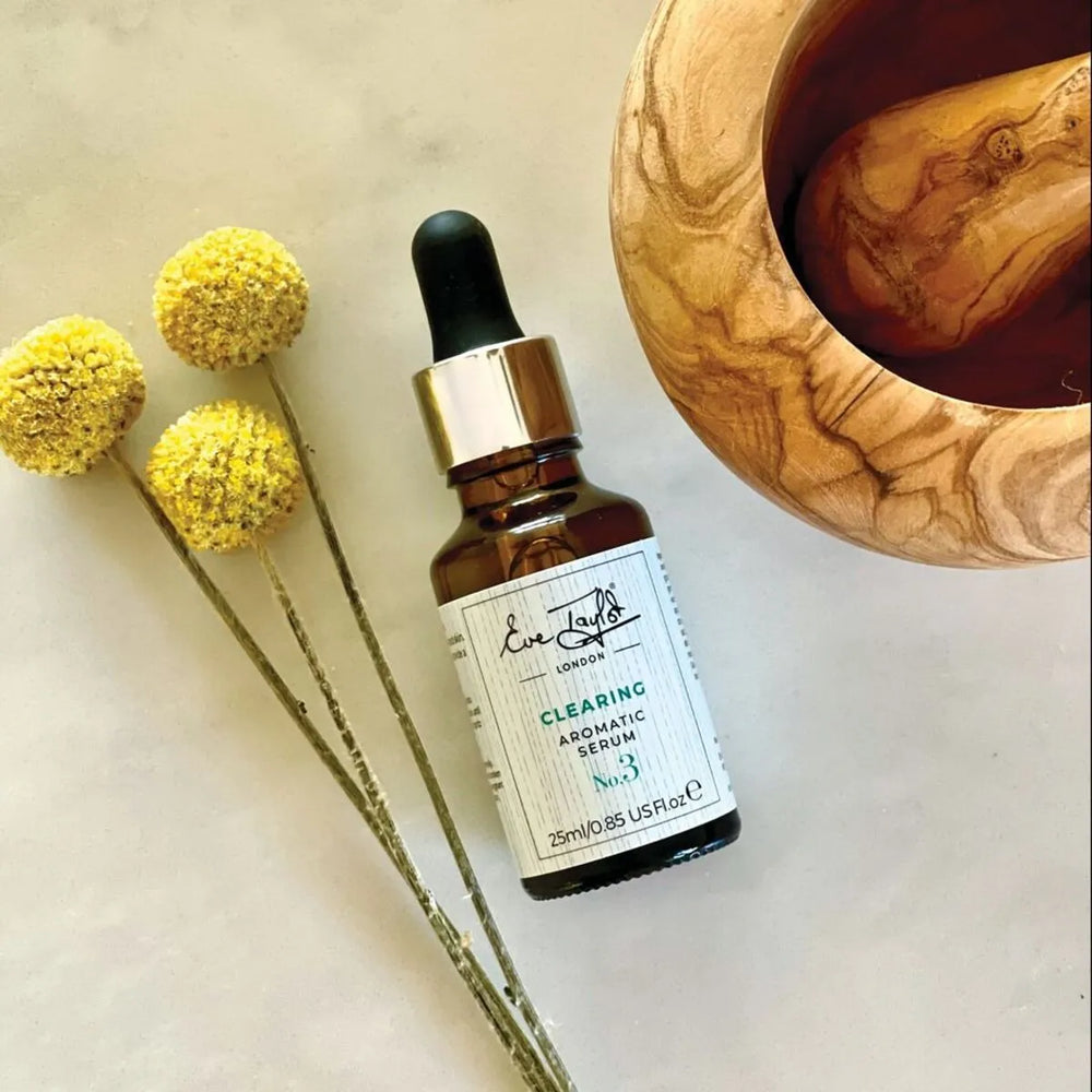 Flaskan är brun och genomskinlig med en svart pipett. Etiketten visar produktnamnet tydligt i vit text. Bakgrunden är vit och enkel, vilket framhäver flaskans eleganta design.