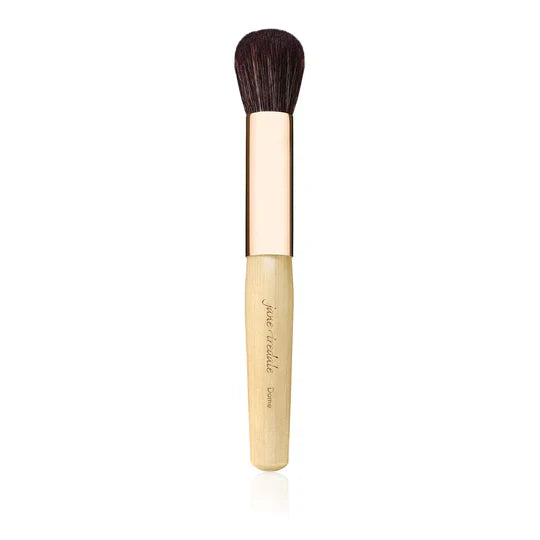 Bild visar en mjuk, kompakt och rundad makeup-borste med tätt sittande strån. Borsten är utformad för att användas tillsammans med bronzers, rouge och highlighters för en jämn och naturlig applicering.