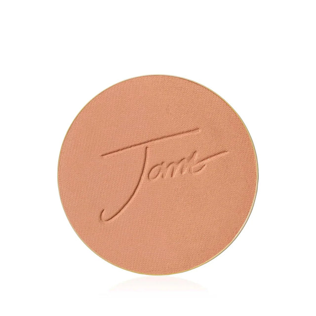 Ett runt bronzing-puder. Pudret har en varm, gyllene ton. Bilden har bra kontrast och visar tydligt pudrets struktur.